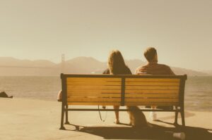 2 people sitting on bench overlooking golden gate bridge