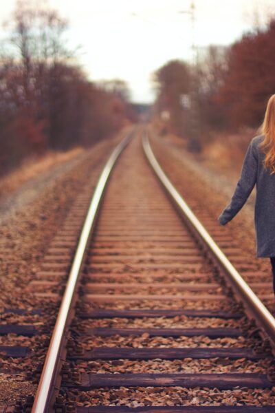 girl walking alone down empty train tracks