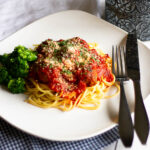 Spaghetti and meatballs plated with fork, knife and napkin