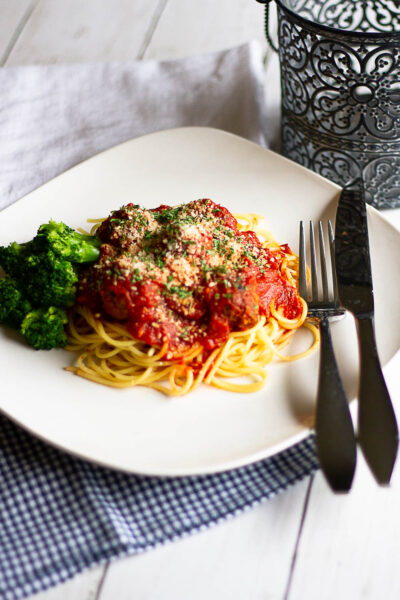 Spaghetti and meatballs plated with fork, knife and napkin