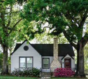exterior of small home with large green trees