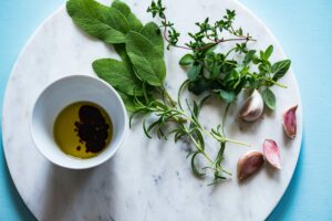 cutting board with herbs and oil/vinegar on it.