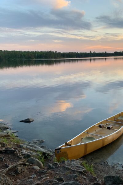 Empty canoe on lake with 1 disappointed person looking out into distance