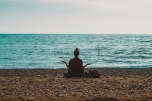 sitting on beach with arms out celebrating margin in life