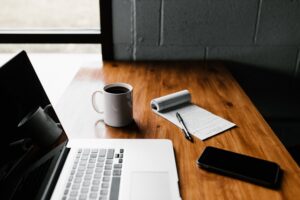 computer, notepad, and coffee cup on desk.