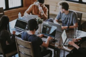 view of 5 people working at table- why do you work?