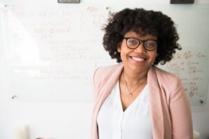 African American woman in pink blazer near whiteboard