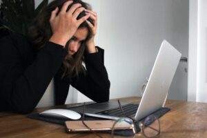 Woman holding her head in front of computer- why do you work?