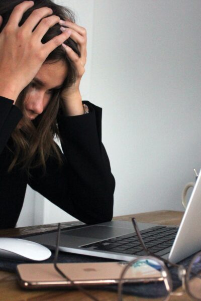 Woman holding her head in front of computer- why do you work?