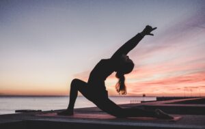 Woman doing yoga pose at sunset on beach