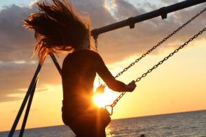 Girl swinging with loose hair during sunset