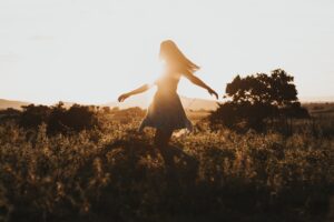 Girl twirling in field during sunset