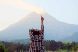 person pointing in air by mountain