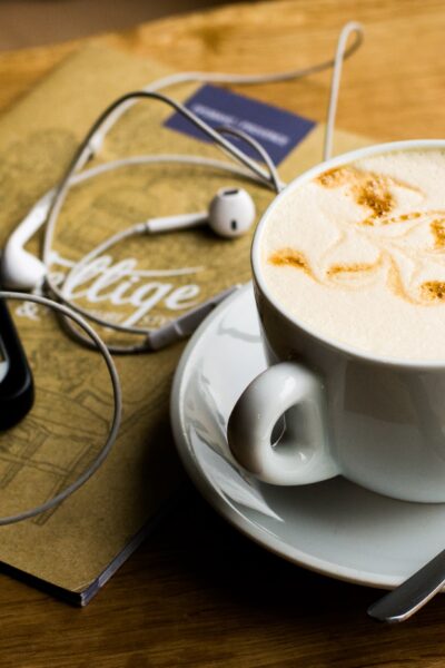 table with coffee, phone, and headphones listening to podcast