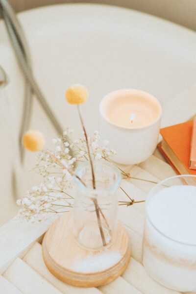 Coffee, flowers, and candle on tray by bathtub
