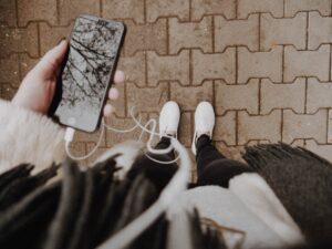 person holding phone looking at feet and ground