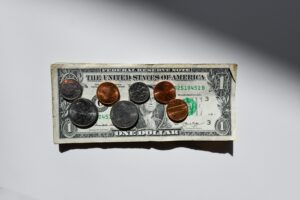 Coins and dollar bills on white table