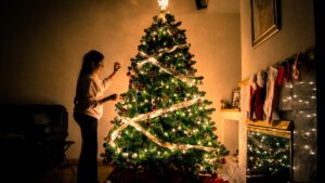 Lit christmas tree with girl decorating it
