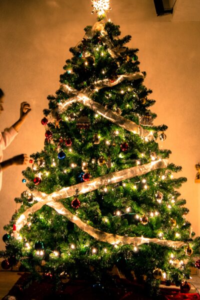 Lit christmas tree with girl decorating it