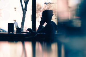 Shadow of person working on laptop at coffee shop