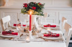 tablescape with candles, dishes, red napkins, and green/red centerpiece
