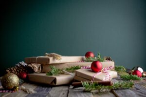 presents piled on table with branches and ornaments around them.