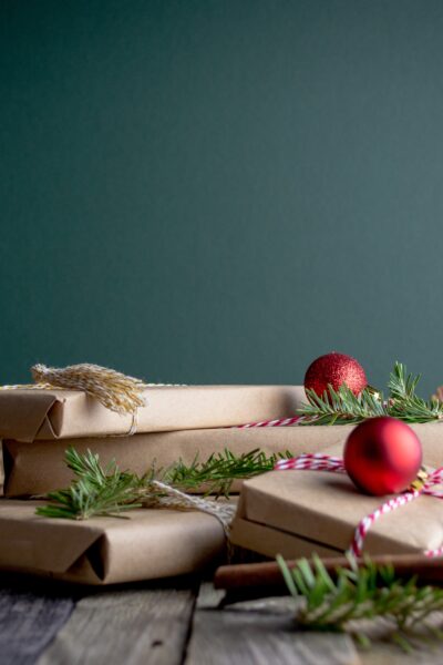 presents piled on table with branches and ornaments around them.