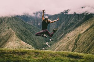 Girl jumping in the air in front of a grassy hill