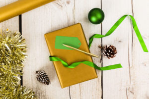 Green and gold gift and wrapping items on white wood table