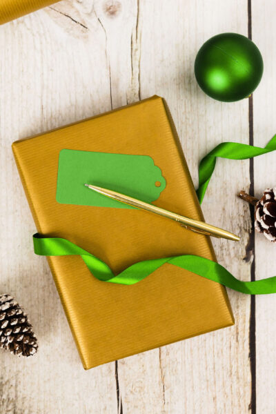 Green and gold gift and wrapping items on white wood table