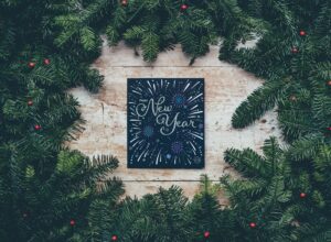 Happy New Year written on small chalk board surrounded by evergreen branches