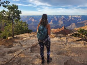 Woman with backpack looking over cliff