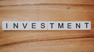 "investment" spelled out in tiles on wooden surface.