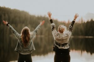 2 women from back with arms raised celebrating