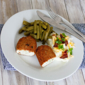 Picture of stuffed chicken breast, loaded mashed potatoes, and green beans on plate.