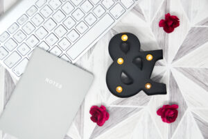 black ampersand on white desk with red flowers