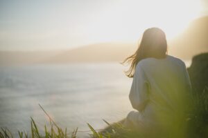 Girl sitting on cliff looking out over ocean