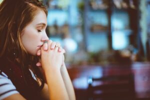 girl holding hands folded under chin with eyes closed