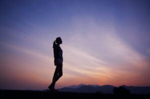 silhouette of woman with purple sunset behind her