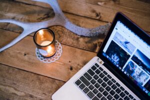 open laptop on wood desk with lit candle.