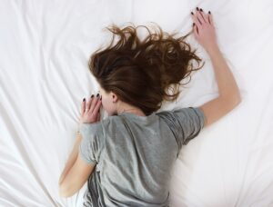 person laying face down in a white bed