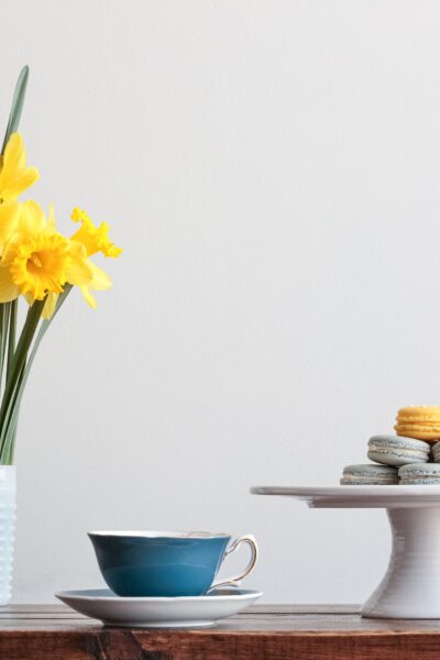 table with cut daffodils, and cake pedestal with dessert on it.
