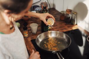 pouring spices into a hot pan cooking