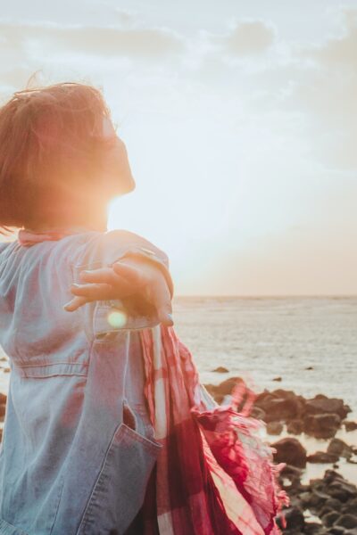 girl with arms outstretched looking at the ocean and happy