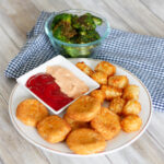Close up picture of air fryer chicken nuggets and tots on plate.