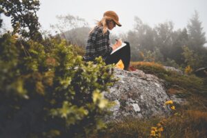 girl sitting on a rock writing in a journal