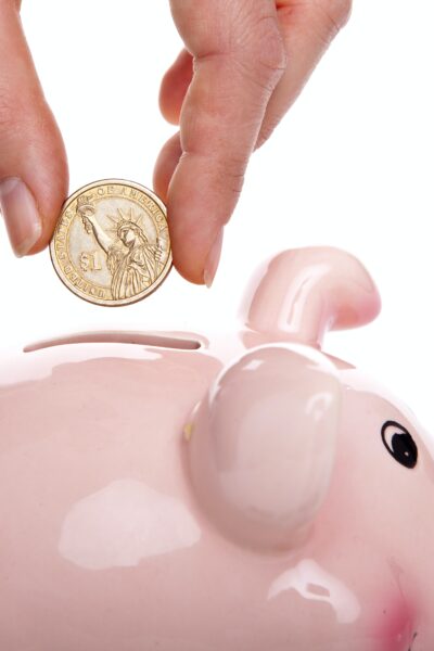 Person putting coin into a piggy bank