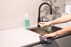 person using a spray cleaner to wipe down counter in a kitchen