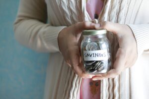 person holding a jar labled savings