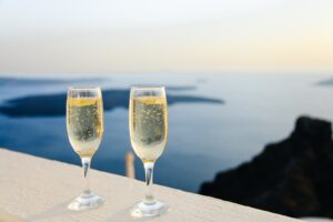 2 glasses of Champaign overlooking view of ocean and islands at sunset